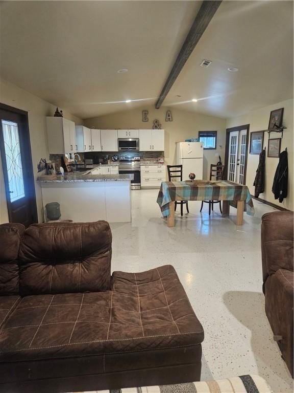 living room with vaulted ceiling with beams and sink