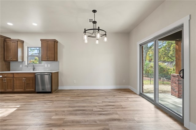 kitchen featuring backsplash, a notable chandelier, hanging light fixtures, light hardwood / wood-style floors, and dishwasher