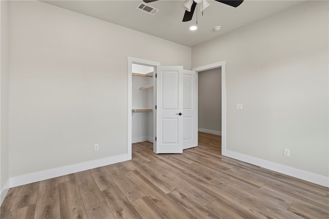 unfurnished bedroom featuring light hardwood / wood-style floors, a spacious closet, ceiling fan, and a closet