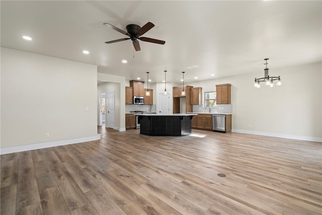 unfurnished living room featuring ceiling fan with notable chandelier, light hardwood / wood-style flooring, and sink