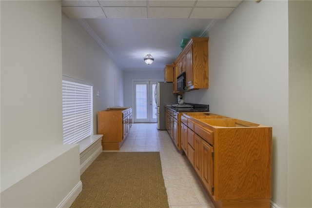 kitchen featuring a drop ceiling, light tile patterned floors, crown molding, and stainless steel fridge