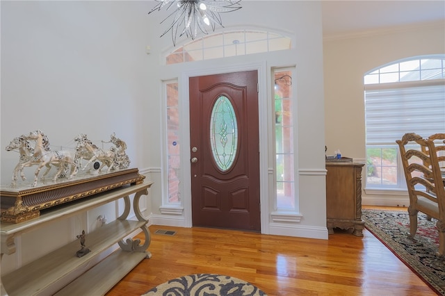 foyer entrance with a wealth of natural light, light wood-type flooring, and ornamental molding