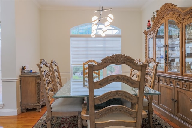 dining room with light wood-type flooring, an inviting chandelier, and crown molding