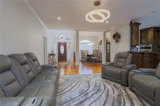 living room with ornamental molding, decorative columns, a notable chandelier, and light hardwood / wood-style floors