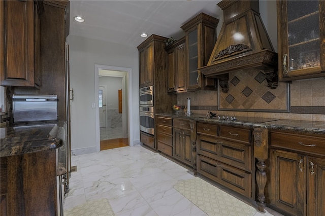 kitchen featuring premium range hood, black electric stovetop, dark stone counters, dark brown cabinetry, and decorative backsplash