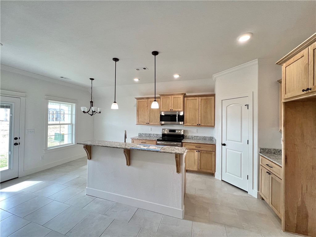 kitchen with an inviting chandelier, a center island with sink, pendant lighting, a breakfast bar, and stainless steel appliances