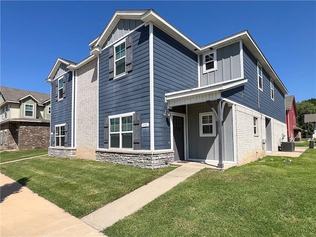 view of front of house with brick siding, central AC unit, board and batten siding, stone siding, and a front lawn