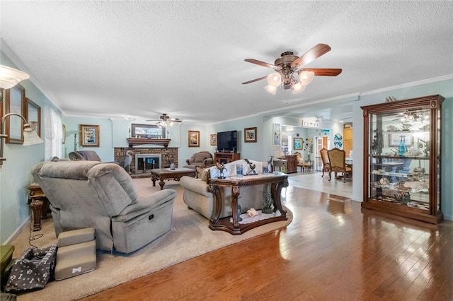 living area with crown molding, a textured ceiling, wood finished floors, and a glass covered fireplace