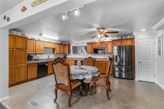 kitchen featuring appliances with stainless steel finishes, brown cabinetry, a sink, and baseboards