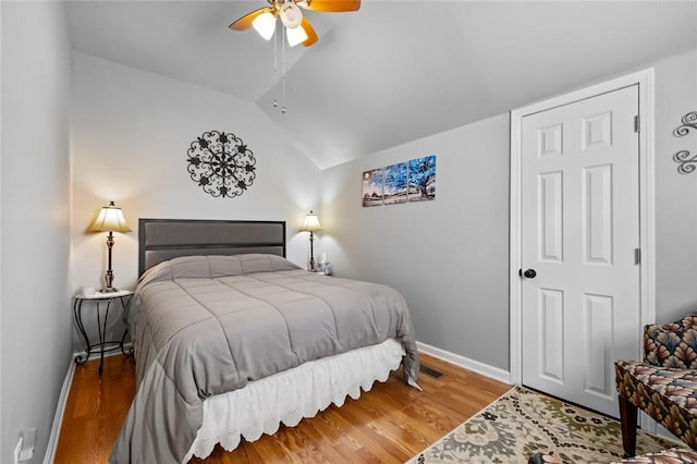 bedroom featuring a ceiling fan, vaulted ceiling, baseboards, and wood finished floors