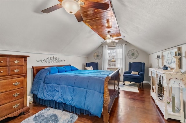 bedroom featuring dark wood-style flooring, vaulted ceiling, a textured ceiling, and ceiling fan