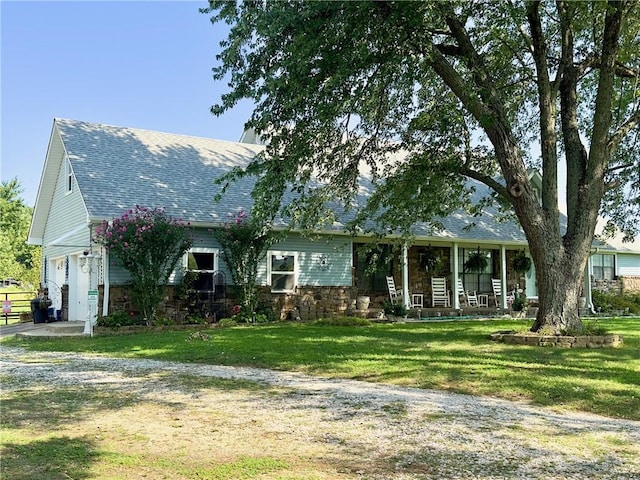 view of front of property featuring a shingled roof, covered porch, an attached garage, a front yard, and driveway