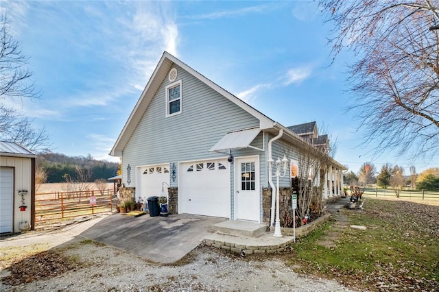 view of home's exterior featuring a garage, fence, and dirt driveway