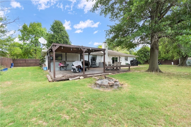 rear view of house featuring a fire pit, a lawn, and a wooden deck