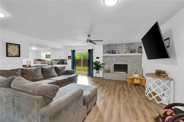 living room featuring a fireplace, light hardwood / wood-style flooring, and ceiling fan