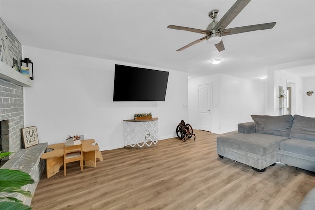 living room featuring light hardwood / wood-style flooring, ceiling fan, and a fireplace