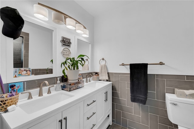 bathroom featuring vanity, toilet, and tile walls