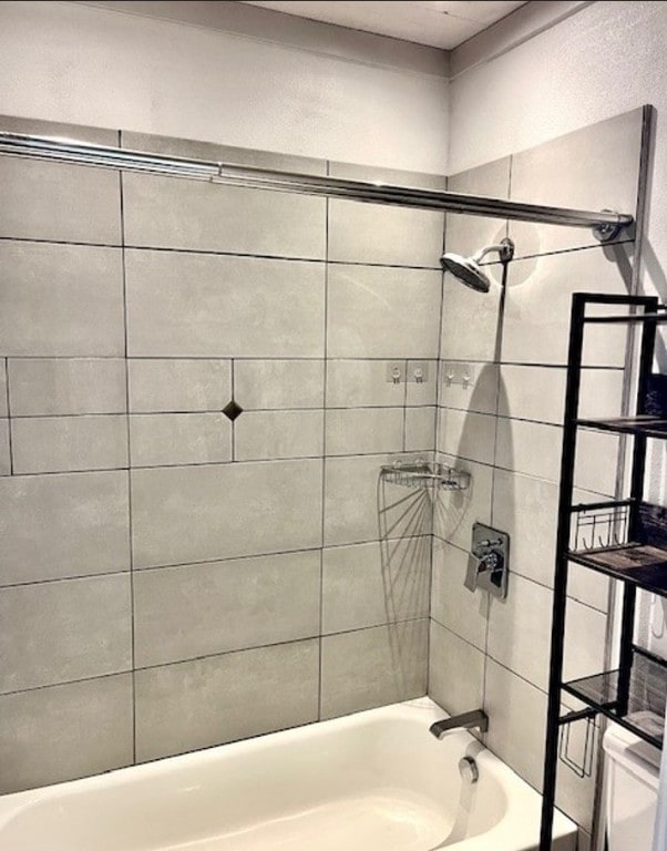 bathroom with tiled shower / bath combo and toilet