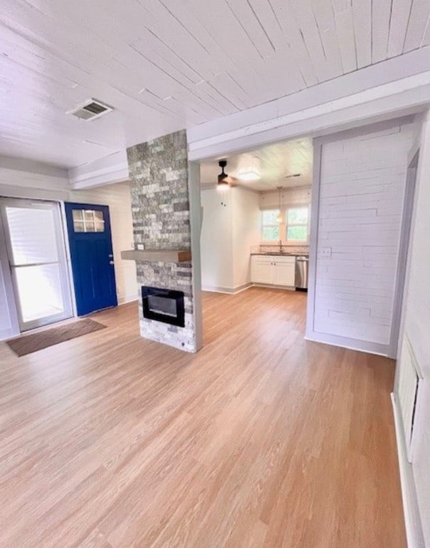 unfurnished living room with ceiling fan, a fireplace, wood ceiling, and light wood-type flooring