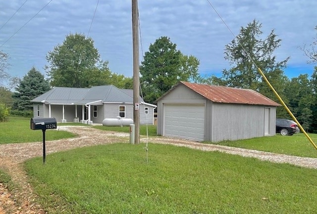 exterior space featuring a front yard, driveway, a detached garage, and an outbuilding