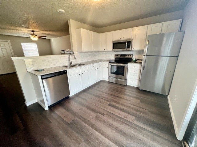 kitchen with dark hardwood / wood-style flooring, stainless steel appliances, sink, white cabinetry, and ceiling fan