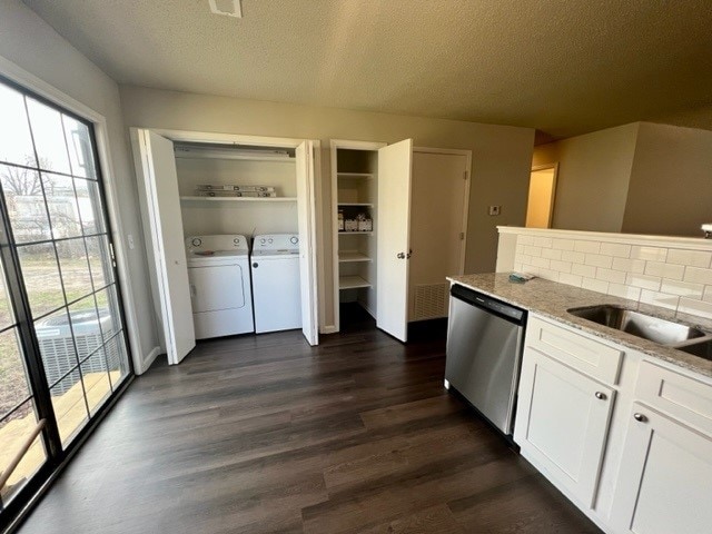 kitchen with washer and clothes dryer, white cabinetry, dishwasher, light stone counters, and dark wood-type flooring