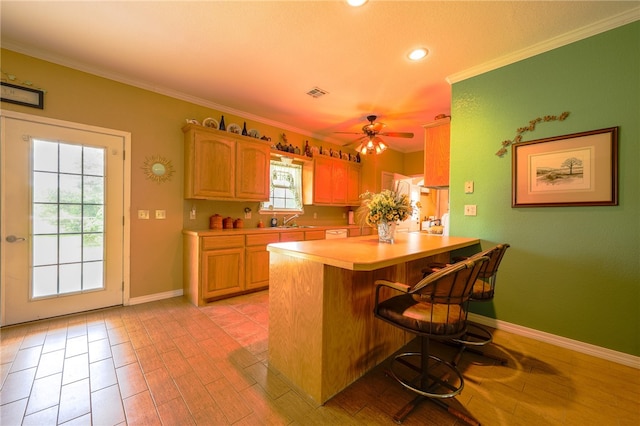 kitchen with crown molding, sink, kitchen peninsula, ceiling fan, and a breakfast bar