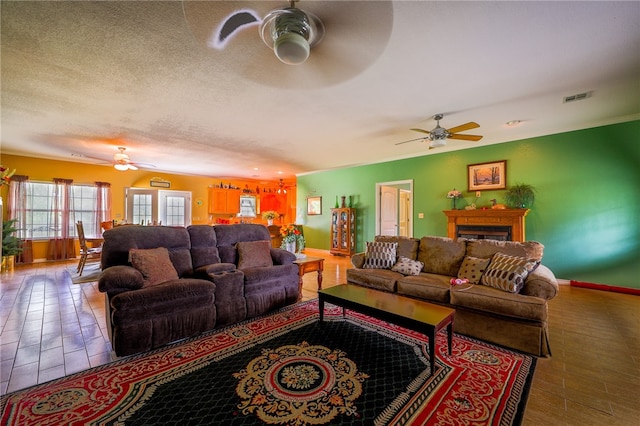 living room with a textured ceiling, ceiling fan, and hardwood / wood-style floors