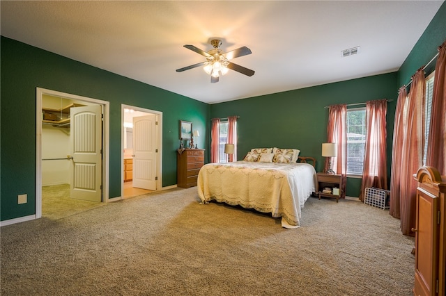 carpeted bedroom with a closet, ceiling fan, a spacious closet, and ensuite bath