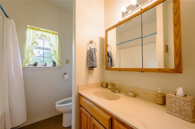 bathroom featuring walk in shower, toilet, and vanity