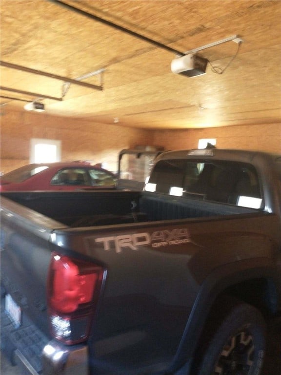 garage with wood ceiling, a garage door opener, and wooden walls