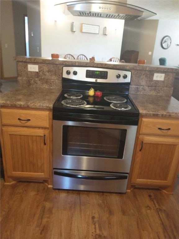 kitchen with dark wood-type flooring, stone countertops, and stainless steel range with electric cooktop