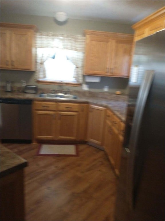 kitchen with appliances with stainless steel finishes, wood-type flooring, and sink