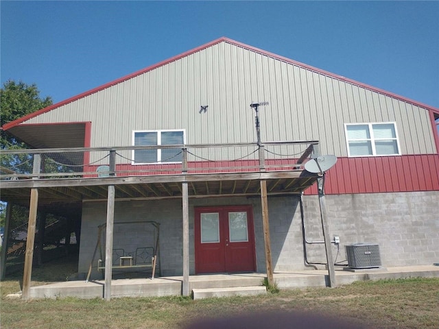 rear view of property with central AC unit, a balcony, and french doors