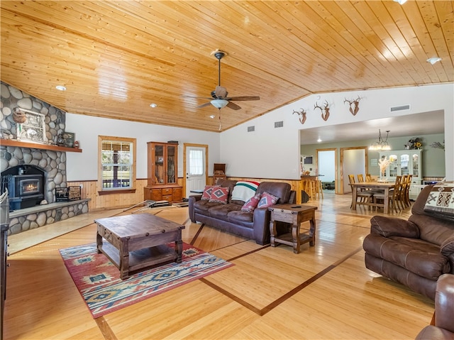 living room featuring wooden walls, light wood-type flooring, wood ceiling, and a wood stove