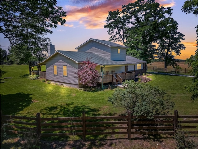 back house at dusk with a yard and a wooden deck