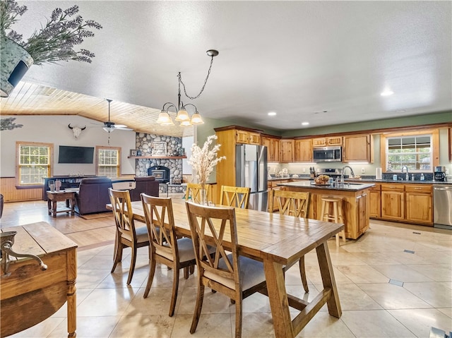 tiled dining room featuring a textured ceiling, vaulted ceiling, sink, and wooden ceiling