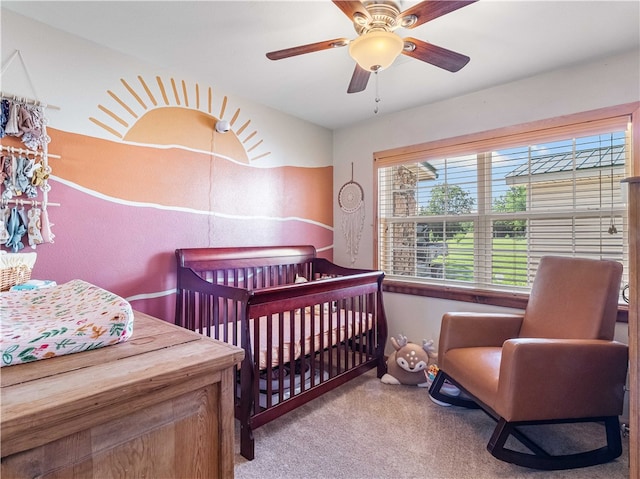 bedroom featuring ceiling fan, a crib, and carpet flooring