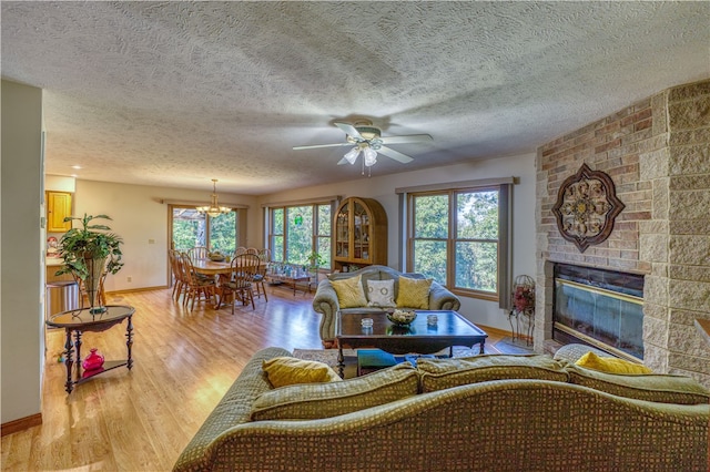 living room featuring light hardwood / wood-style flooring, a large fireplace, a textured ceiling, and plenty of natural light