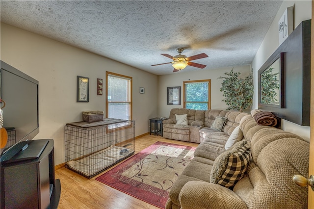 living room with ceiling fan, a textured ceiling, and light wood-type flooring