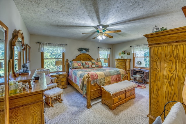 carpeted bedroom with ceiling fan and a textured ceiling