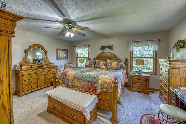 carpeted bedroom with ceiling fan and a textured ceiling