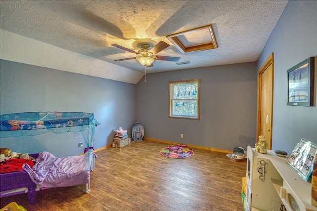 recreation room featuring a textured ceiling, vaulted ceiling, hardwood / wood-style floors, and ceiling fan