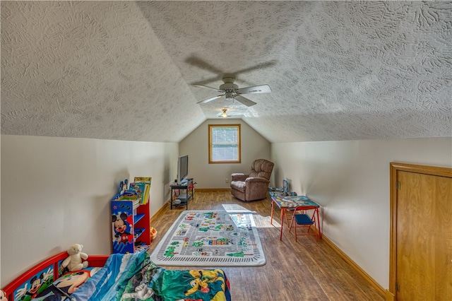 playroom with wood-type flooring, a textured ceiling, lofted ceiling, and ceiling fan