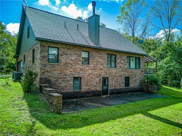 rear view of house with cooling unit, a lawn, and a patio area