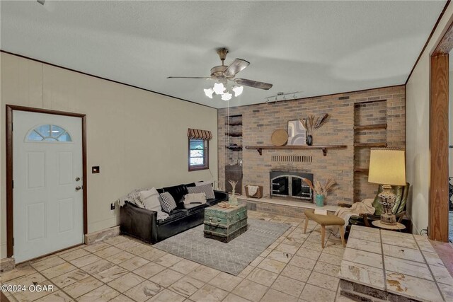 living room with a brick fireplace, a textured ceiling, and ceiling fan