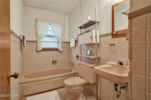 bathroom with tile walls, a washtub, sink, and toilet