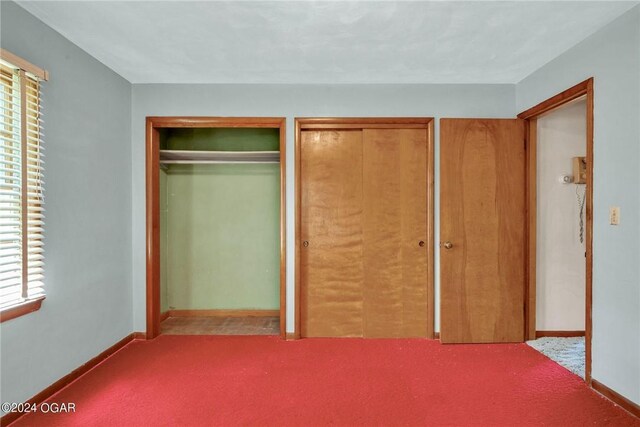 unfurnished bedroom with light colored carpet and multiple closets