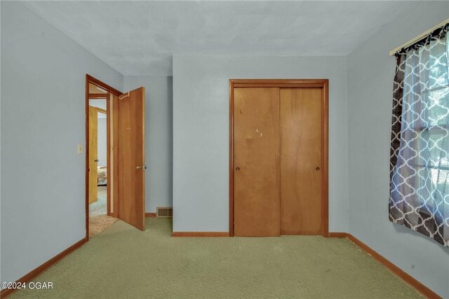 unfurnished bedroom featuring a closet and light carpet