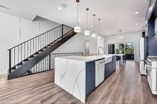 kitchen with white fridge, a spacious island, decorative light fixtures, stainless steel dishwasher, and light hardwood / wood-style floors